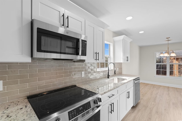 kitchen with sink, stainless steel appliances, light stone countertops, white cabinets, and decorative backsplash