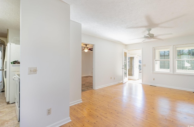 empty room featuring baseboards, light wood-style flooring, a textured ceiling, and ceiling fan