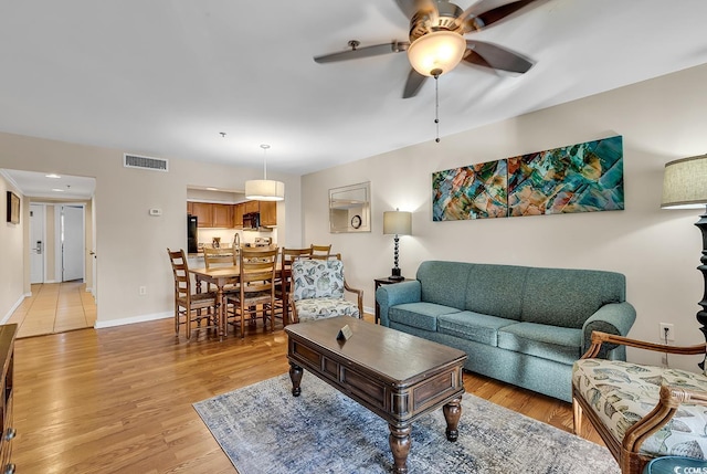 living room with ceiling fan and light hardwood / wood-style flooring