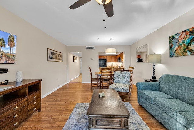 living room featuring ceiling fan and light wood-type flooring