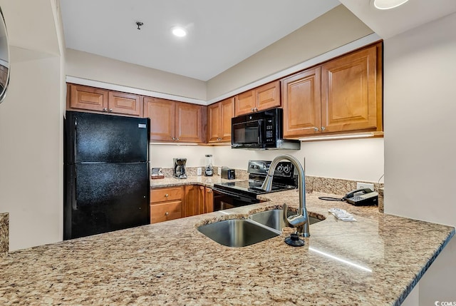 kitchen with light stone countertops, sink, black appliances, and kitchen peninsula