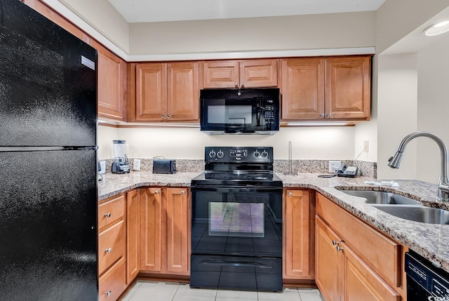 kitchen featuring light stone counters, light tile patterned floors, sink, and black appliances