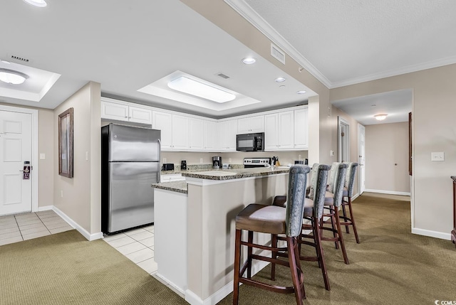 kitchen with a kitchen bar, stainless steel refrigerator, white cabinets, and light tile patterned flooring