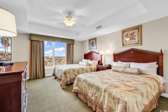 bedroom with carpet floors, ceiling fan, and a tray ceiling