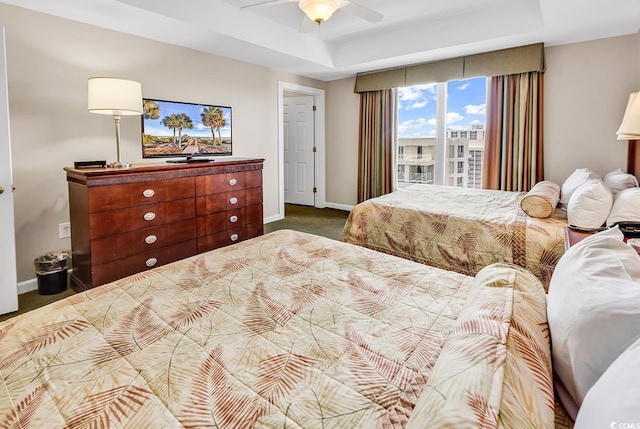 bedroom featuring ceiling fan, a raised ceiling, and carpet