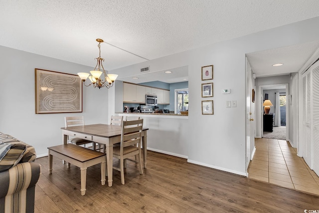 dining room with hardwood / wood-style flooring, an inviting chandelier, and a textured ceiling