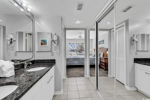 bathroom featuring tile patterned flooring, vanity, ceiling fan, and a textured ceiling