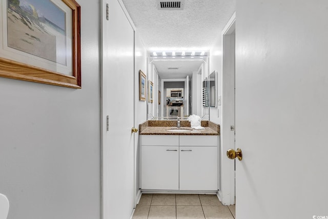 bathroom featuring vanity, tile patterned floors, and a textured ceiling