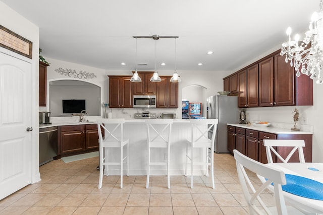 kitchen with a kitchen bar, sink, a center island, appliances with stainless steel finishes, and pendant lighting