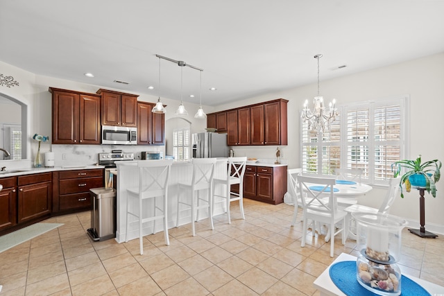 kitchen with stainless steel appliances, pendant lighting, a breakfast bar, a center island, and sink