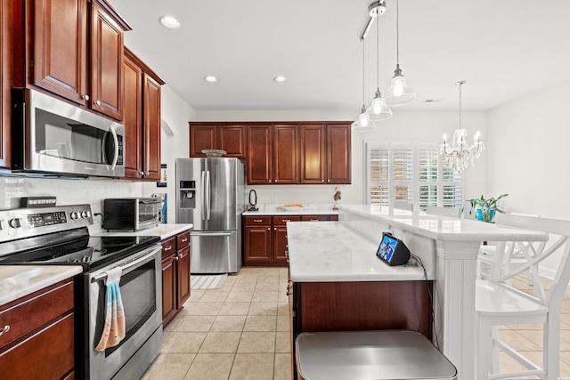 kitchen with light tile patterned flooring, a kitchen bar, a center island, pendant lighting, and stainless steel appliances