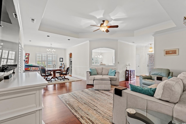 living room with dark hardwood / wood-style flooring, a tray ceiling, ceiling fan with notable chandelier, and crown molding