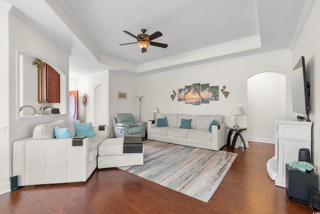 living room featuring ornamental molding, dark hardwood / wood-style floors, and a tray ceiling