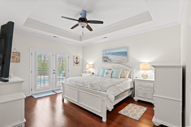 bedroom with access to outside, a tray ceiling, crown molding, dark wood-type flooring, and french doors