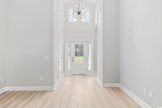 entrance foyer featuring an inviting chandelier, light hardwood / wood-style floors, and a high ceiling