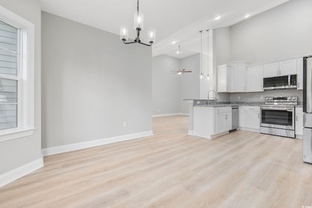 kitchen featuring white cabinetry, stainless steel appliances, light hardwood / wood-style floors, ceiling fan with notable chandelier, and kitchen peninsula