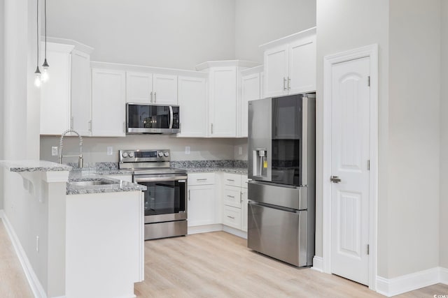 kitchen featuring stainless steel appliances, white cabinetry, hanging light fixtures, and sink