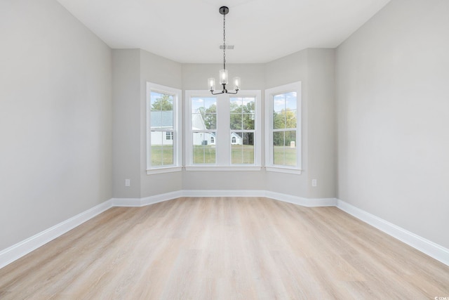 spare room with light hardwood / wood-style floors and a notable chandelier