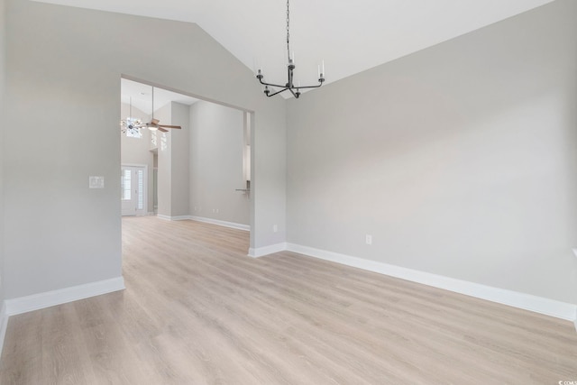 empty room with ceiling fan with notable chandelier, vaulted ceiling, and light hardwood / wood-style floors