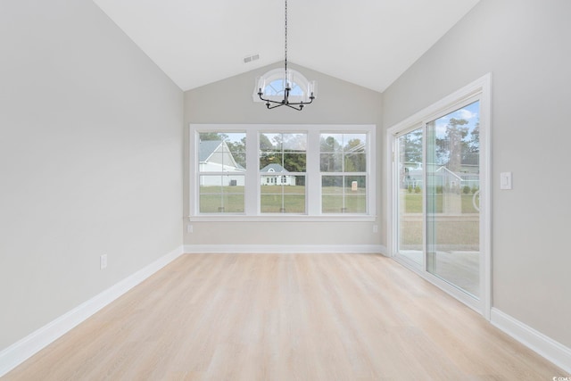 unfurnished dining area featuring vaulted ceiling, an inviting chandelier, and light hardwood / wood-style floors