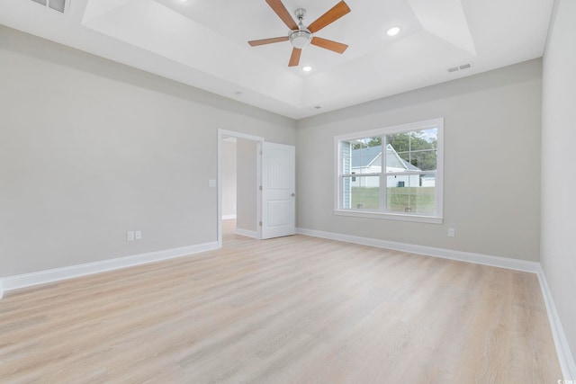 unfurnished room with ceiling fan, a raised ceiling, and light hardwood / wood-style floors