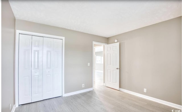 unfurnished bedroom with a closet, wood finished floors, and baseboards