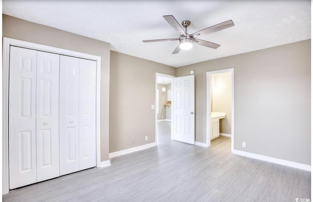 unfurnished bedroom featuring baseboards, connected bathroom, ceiling fan, light wood-style floors, and a closet