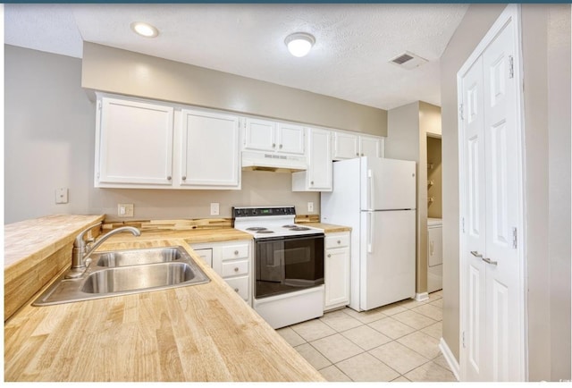 kitchen featuring under cabinet range hood, white appliances, a sink, white cabinets, and washer / dryer