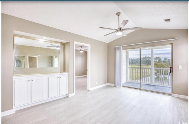 interior space featuring lofted ceiling, a ceiling fan, visible vents, baseboards, and light wood finished floors