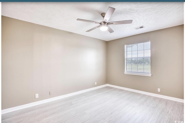 unfurnished room featuring a ceiling fan, visible vents, baseboards, and wood finished floors