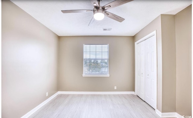 unfurnished bedroom featuring baseboards, visible vents, a ceiling fan, light wood-style flooring, and a closet