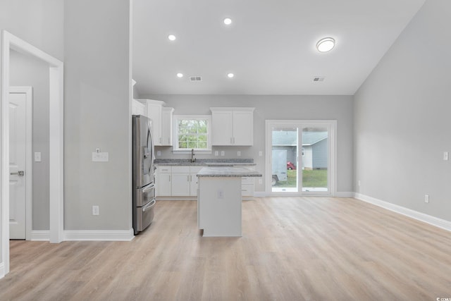 kitchen featuring sink, light hardwood / wood-style floors, white cabinets, a kitchen island, and stainless steel fridge with ice dispenser