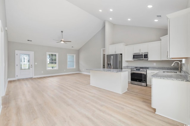 kitchen featuring sink, light hardwood / wood-style flooring, stainless steel appliances, a center island, and white cabinets