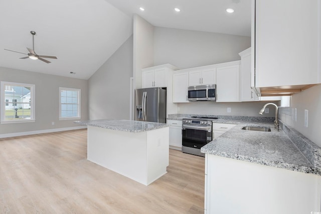 kitchen featuring sink, appliances with stainless steel finishes, white cabinetry, light stone countertops, and a kitchen island