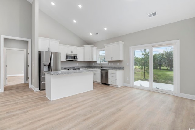 kitchen with a kitchen island, white cabinetry, appliances with stainless steel finishes, and light stone countertops