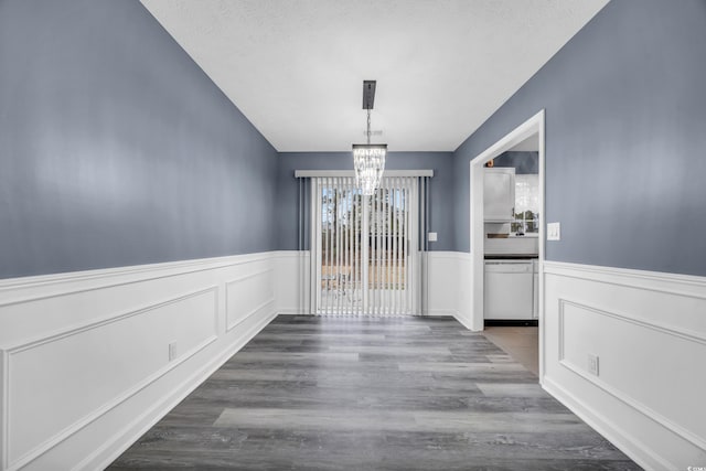 unfurnished dining area with wood-type flooring, a textured ceiling, and a notable chandelier