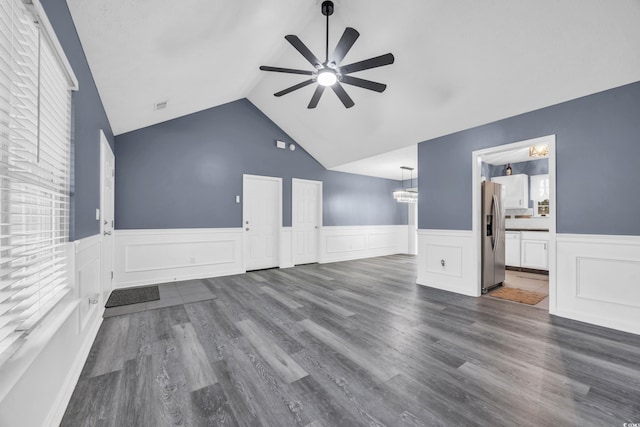 unfurnished living room with vaulted ceiling, dark hardwood / wood-style flooring, ceiling fan with notable chandelier, and a wealth of natural light