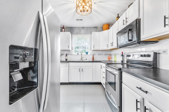 kitchen featuring appliances with stainless steel finishes, sink, light tile patterned floors, and white cabinets