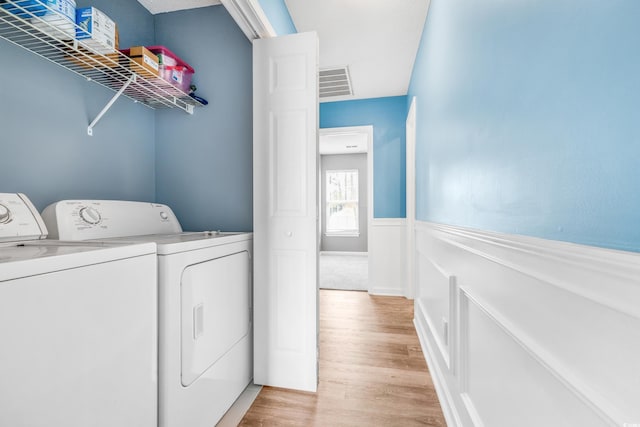 clothes washing area featuring washer and clothes dryer and light hardwood / wood-style floors