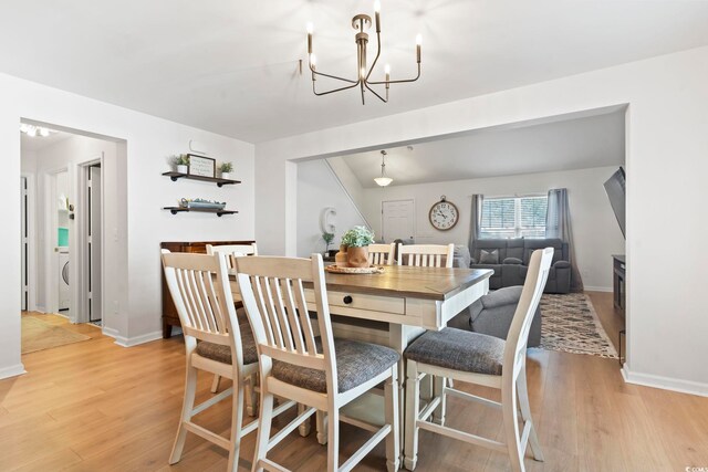 dining room with washer / clothes dryer, light hardwood / wood-style flooring, and a chandelier