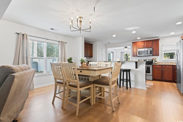 dining space featuring a notable chandelier, a wealth of natural light, and light wood-type flooring