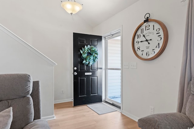 foyer entrance with plenty of natural light, lofted ceiling, and light hardwood / wood-style flooring