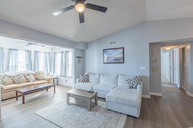 living room with dark wood-style floors, lofted ceiling, visible vents, and ceiling fan