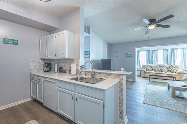 kitchen with light countertops, decorative backsplash, a sink, dishwasher, and a peninsula