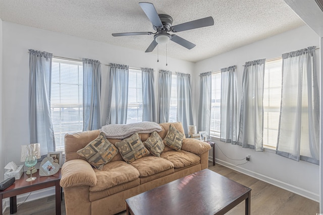 living room featuring ceiling fan, a textured ceiling, baseboards, and wood finished floors