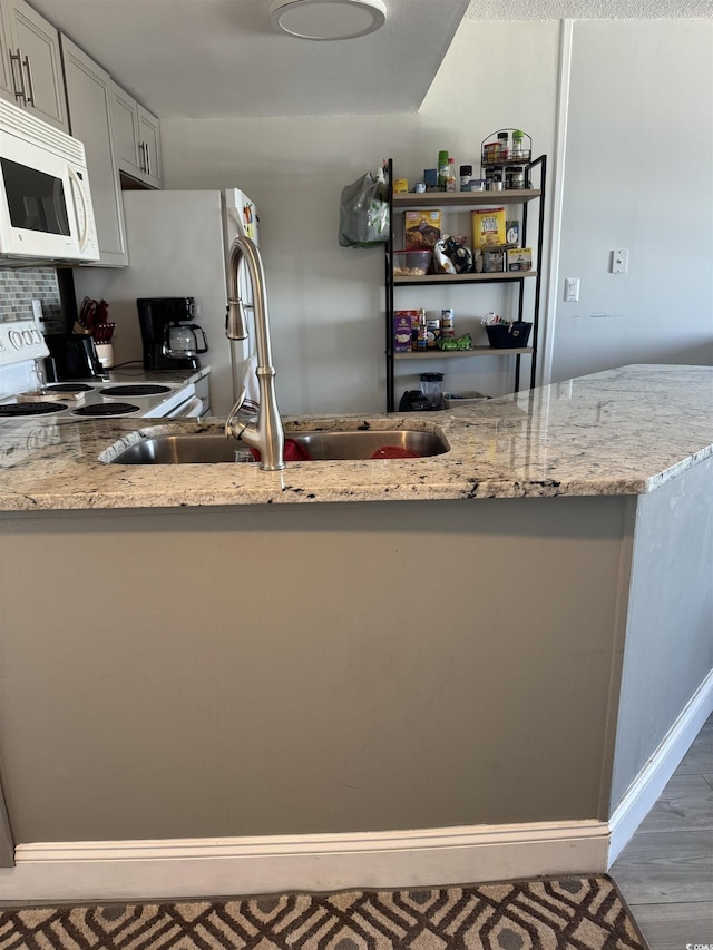 kitchen with sink, white appliances, white cabinetry, light stone counters, and tasteful backsplash