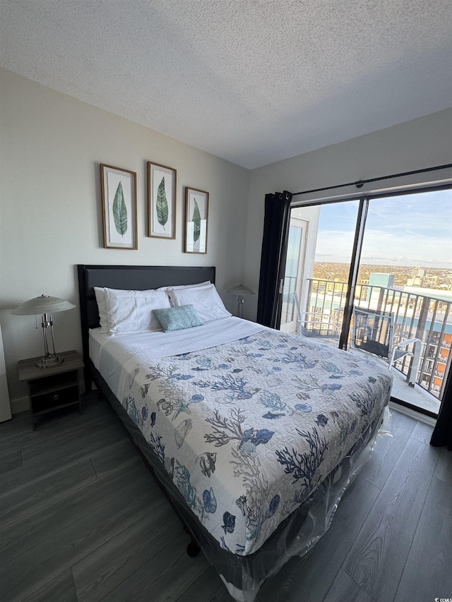 bedroom with access to exterior, dark wood-type flooring, and a textured ceiling