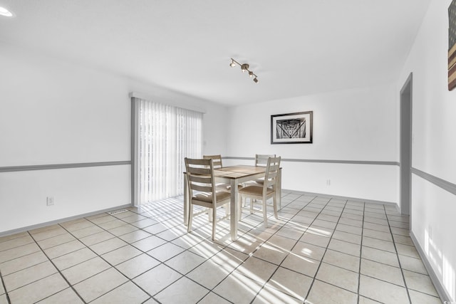 dining area featuring rail lighting and light tile patterned flooring