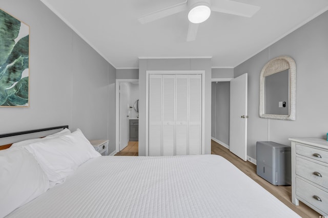 bedroom with connected bathroom, light hardwood / wood-style flooring, ornamental molding, a closet, and ceiling fan