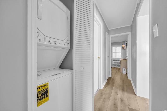 clothes washing area with light hardwood / wood-style flooring and stacked washer / dryer